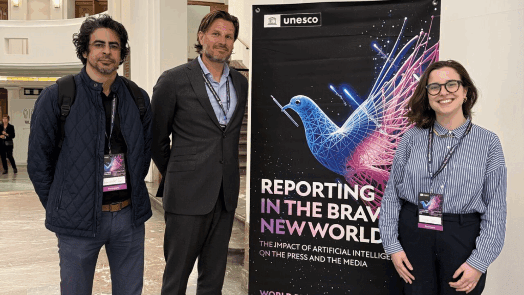 Hassan (left), Wouter (center) and Giovana (right) post in front of a standing banner at the World Press Freedom Day event in Brussels
