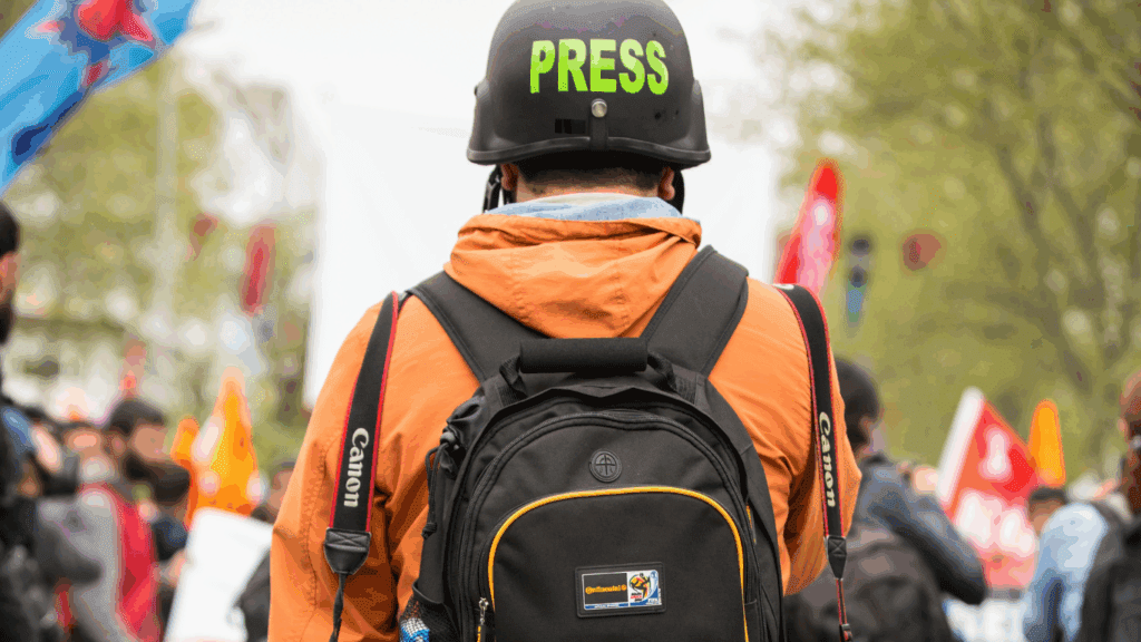 A reporter stands looking into a crowd